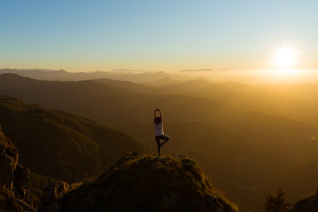 Person stretching on a mountain summit at sunrise